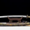 A decorative Chinese Dao sword displayed on a wooden stand with its scabard below on the floor.