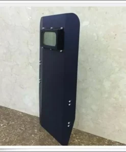 A full body, tactical ballistic shield leaning against a wall.