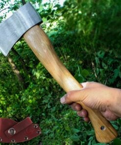 A hand holding a small hand axe with a wooden handle, along with its axe sheath displayed below, against a jungle background.