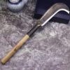 A hand sickle tool with a curved blade and wooden handle.