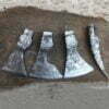 Four axe heads laying on the ground.