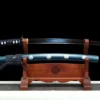 A blue colored Wakizashi sword and its scabbard displayed on a wooden stand.