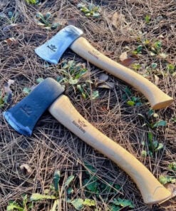 Two small camp axes displayed lying side-by-side on a forest floor.