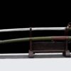 A one handed cavalry saber sword and its army green scabbard displayed on a wooden stand.