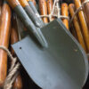 A used Chinese military shovel within a large pile of army shovels.
