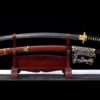 A Tachi curved blade sword displayed next to its scabbard, on a small wooden sword-stand.