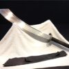A Chinese Dadao sword displayed against a white sheet, with its scabbard below.