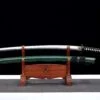 A folded, Damascus steel Katana, displayed next to its green scabbard, on a small wooden sword-stand.