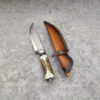 A hunting deer antler knife, displayed next to its leather sheath.