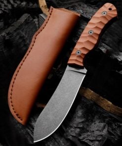 A deer skinning knife and its leather sheath lying on charcoal wood.