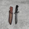 A wood handled fixed Damascus steel blade fighting knife next to its leather sheath, lying on a grey concrete floor.