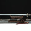 A straight, double edged Chinese Jian sword and its decorative scabbard displayed on a wooden stand.