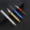 Four small keychain knife tools leaning against a black box.
