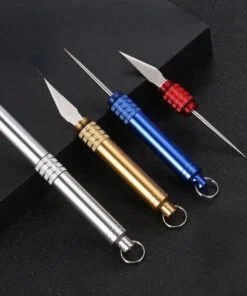 Four small keychain knife tools leaning against a black box.