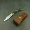A folding lockback knife next to its leather pouch, lying on a floor.