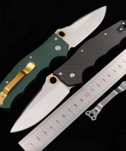 Two folding lockblade knives with silver colored blades opened, next to a steel ruler.