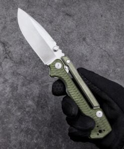 A hand with black glove holding a survival military folding knife with army green color handle.