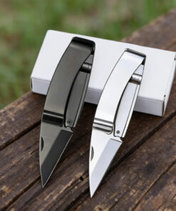 Two money clip knife models of differing colors displayed leaning against a small white box.