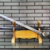 A sun and moon themed straight Chinese Jian sword with its scabbard displayed on a wooden stand, with a brick wall background.