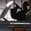 A straight single edge Ninja sword and its scabbard displayed on a wooden stand, with close-ups of the blade tip and a man wearing a Ninja outfit above.