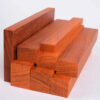Multiple blocks of African Padauk wood stacked.
