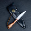A small rabbit knife, displayed lying against its sheath.