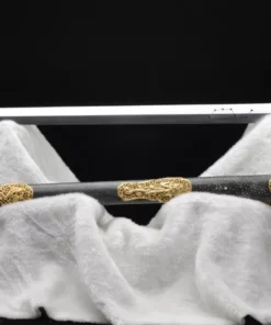 A Chinese Jian, straight sword displayed nect to its decorative scabbard, upon a white cloth sheet.