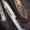 A fixed blade tactical bowie knife, displayed next to its leather sheath.