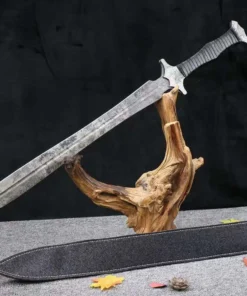 A modern tactical sword displayed on a small wood log, with its scabbard below on the floor.