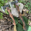 A small woodsman axe and forest hatchet, displayed side-by-side against a forest floor.