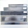 Four stainless steel material knife blanks next to a measurement ruler.