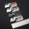 Four mini key ring knives next to a measurement ruler.