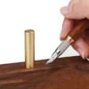 A hand scribing into wood with a pen knife scribing tool.