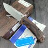 A folding bushcraft knife lying against its knife box.