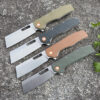 Four folding cleaver pocket knives with different color handles and blades opened, lying against rock ground.