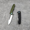 Two folding knives with different color handles lying on a concrete floor; one with blade opened and the other with blade closed.
