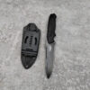 A fixed blade tactical knife and its sheath lying on a concrete floor.