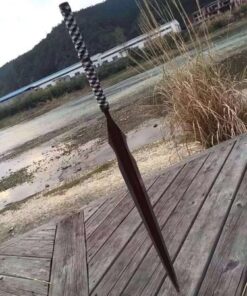 A long blade spear sword, with its blade stuck into wooden deck flooring.