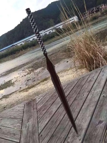 Long Blade Spear A long blade spear sword, with its blade stuck into wooden deck flooring.