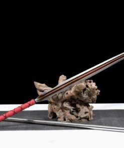 A long bladed spear sword displayed leaning against a wood log, with its pole handle extension on the floor below.