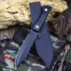 A fixed blade survival knife and its leather sheath, lying on a small camouflage bag.