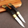 Two different sized folding traditional pocket knives with blades opened, leaning against a wood chopping board.