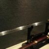 A Miao Dao, Chinese two handed sword, displayed on a wooden stand, with its scabbard below.