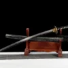 A gold dragon sword Katana displayed next to its scabbard, on a small wooden sword-stand.