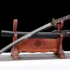 A Japanese sword wakizashi and its scabbard displayed on a wooden sword stand.