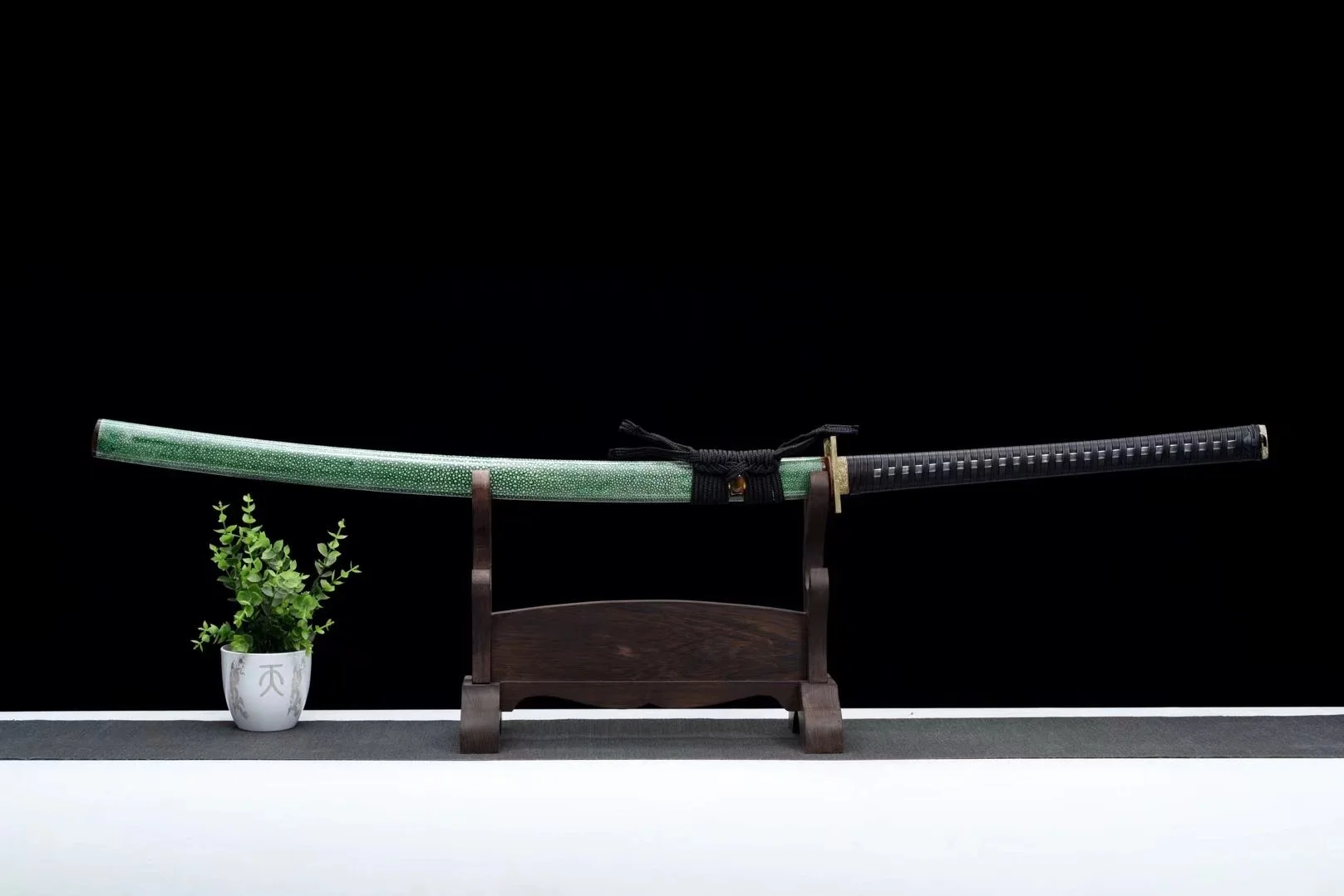 Nagamaki sword A long Nagamaki sword sheathed within its green scabbard, displayed on a wooden stand.