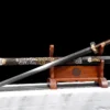A Chinese sacred sword Jian displayed next to its decorated scabbard, on a wooden sword stand.