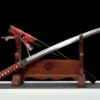 A Samurai Wakizashi sword and its scabbard leaning against a wooden sword stand.
