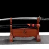 A short Japanese sword and its scabbard displayed on a wooden sword stand.