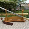 A straight single edged sword flute with its flute sheath displayed on a wooden stand.
